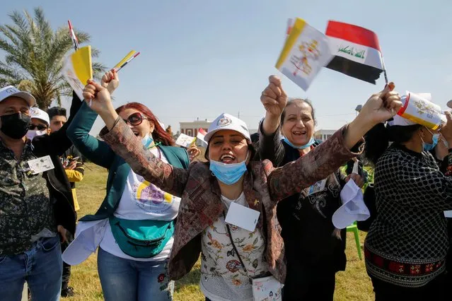 People holding Iraqi and Vatican flags as they wait for the arrival of Pope Francis, at Baghdad Airport Road, in Baghdad, Iraq on March 5, 2021. (Photo by Thaier al-Sudani/Reuters)