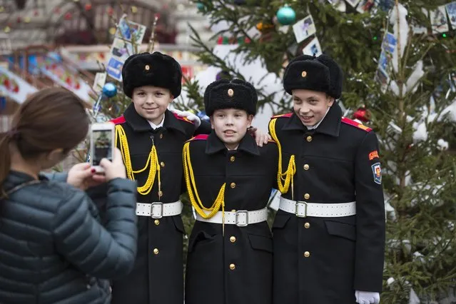 Russian cadets pose for a photo in Red Square, decorated to celebrate the upcoming Christmas and New Year in Moscow, Russia, Tuesday, December 22, 2015. It's usually the cold that's bitter in Moscow in December, but this year it's the humor that bites during an unusual warm spell and temperatures climbed as high as 10 degrees Celsius (50 degrees Fahrenheit).  (Photo by Alexander Zemlianichenko/AP Photo)