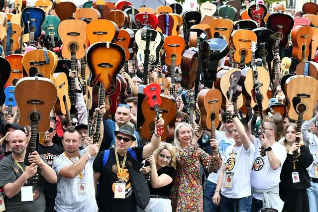 Guitarists raise their instruments during a mass gathering of guitar players in an attempt to beat the Guinness record for ensemble guitar playing, in Wroclaw, Poland, 01 May 2022. A total of 7,676 guitarists took part in the successful attempt to set a new world record, gathering 253 more guitarists than in 2019, when the previous record was set. During the event, the participating guitarists arranged a heart shape with their instruments raised to show their solidarity and support for Ukraine. (Photo by Maciej Kulczynski/EPA/EFE)