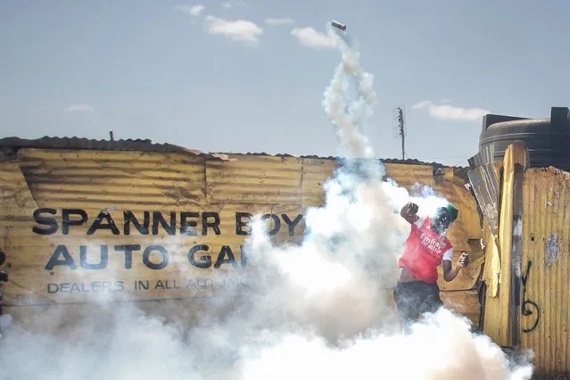 A protester hurls back a tear gas cannister in the direction of the Kenyan police on the third-day of confrontations between authorities and supporters of the Kenyan opposition  during anti-government protests in Kibera, Nairobi, on July 21, 2023. (Photo by Tony Karumba/AFP Photo)