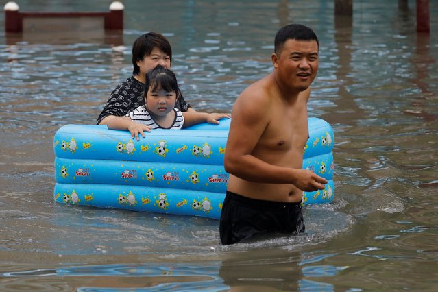 People make their way through floodwaters at a residential compound after the rains and floods brought by remnants of Typhoon Doksuri, in Zhuozhou, Hebei province, China on August 3, 2023. (Photo by Tingshu Wang/Reuters)