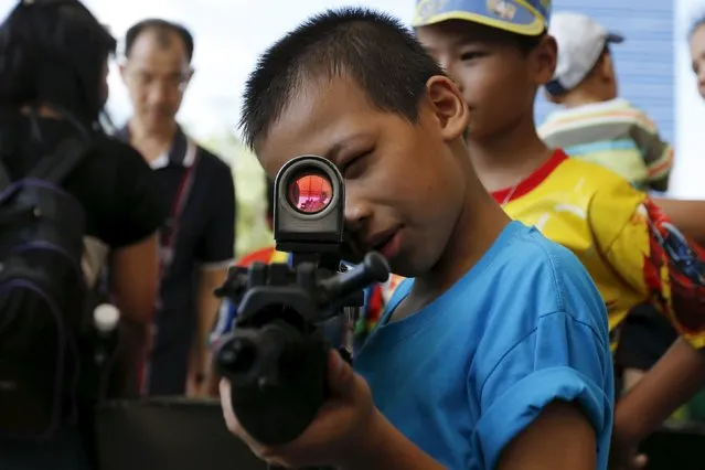 A boy plays with a weapon during the Children's Day celebration at a military facility in Bangkok, Thailand January 9, 2016. (Photo by Jorge Silva/Reuters)