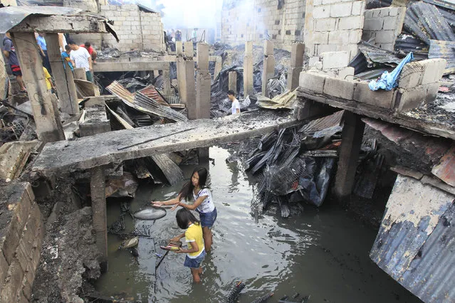 Residents search for reusable items after a fire hit a residential area at Merville park in Pasay city, metro Manila February 16, 2015. At least four people were killed after a fire razed an estimated 300 houses made of light materials, local media reported. (Photo by Romeo Ranoco/Reuters)