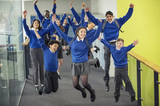 Enthusiastic high school students wearing school uniforms smiling and jumping in school corridor. (Photo by Chris Ryan/Getty Images/Caiaimage)