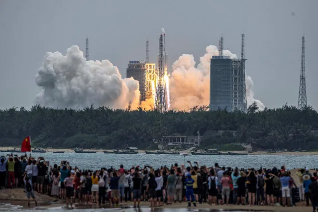 People watch a Long March 5B rocket, carrying China's Tianhe space station core module, as it lifts off from the Wenchang Space Launch Center in southern China's Hainan province on April 29, 2021. (Photo by AFP Photo/China Stringer Network)