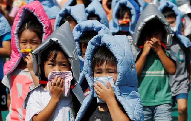 School children wearing padded hoods to protect them from falling debris, take part in an earthquake simulation drill at an elementary school in Tokyo, Japan August 31, 2018, a day before Disaster Prevention Day to commemorate the 1923 Great Kanto earthquake. (Photo by Toru Hanai/Reuters)