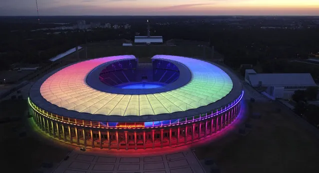 The sun sets behind the rainbow-illuminated Olympic Stadium in Berlin, Germany, Wednesday, June 23, 2021. The UEFA did not allow the city of Munich to illuminate the Allianz Arena stadium in rainbow colors during the Euro 2020 soccer match between Germany and Hungary on Wednesday. (Photo by Michael Sohn/AP Photo)