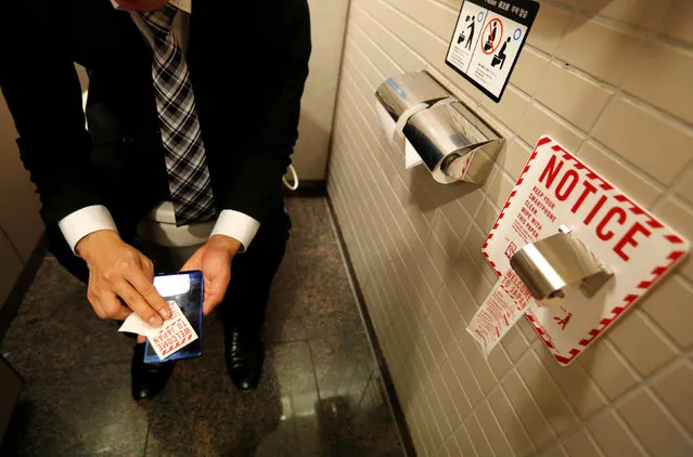 A man demonstrates a toilet roll for wiping smartphones, installed by Japanese mobile phone company NTT Docomo, in a high-tech bathroom equipped with bidet and heated seat at Narita international airport in Narita, Japan, December 28, 2016. (Photo by Toru Hanai/Reuters)