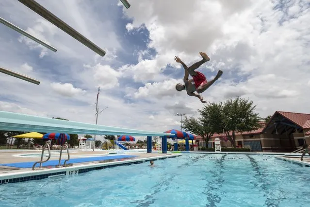 Lifeguard Dshybroen Deary jumps off a diving board during a break while working at the Woodson Park Aquatic Center Wednesday, June 2, 2021, in Odessa, Texas. (Photo by Eli Hartman/Odessa American via AP Photo)