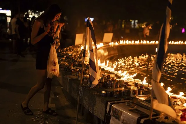 A woman stands in front of lighted candles in honour of victims of the Hamas attacks during a vigil at the Dizengoff square in central Tel Aviv, Israel, on Wednesday, October 18, 2023. At a time when world sentiment has begun to sour on Israel's devastating airstrikes in Gaza, the vast majority of Israelis, across the political spectrum, are convinced of the justice of the war. (Photo by Petros Giannakouris/AP Photo)