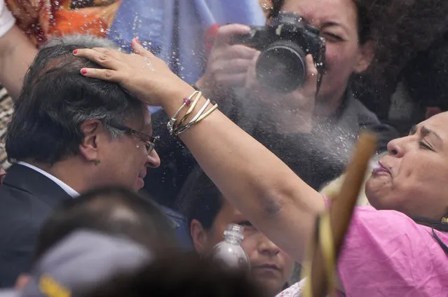 An Indigenous woman spits water onto the head of President-elect Gustavo Petro, during a 'popular and spiritual' inauguration ceremony presided over by local Indigenous groups and feminist activists, in Bogota, Colombia, Saturday, August 6, 2022. Petro, the first left-wing Colombian president in 200 years, will be sworn in as the country’s new president on Sunday, Aug. 7.  (Photo by Ariana Cubillos/AP Photo)