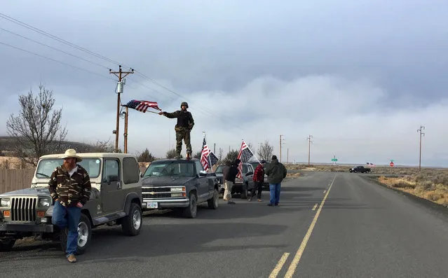 People wave American flags near the Malheur National Wildlife Refuge, Thursday, February 11, 2016, near Burns, Ore. The last four armed occupiers of the national wildlife refuge in eastern Oregon said they would turn themselves in Thursday morning, after law officers surrounded them in a tense standoff. (Photo by Rebecca Boone/AP Photo)