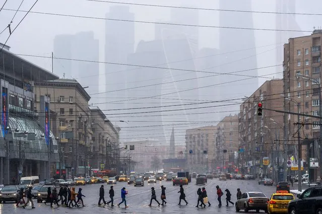 People cross a road in central Moscow, with the buildings of the Moscow International Business Center (Moskva City) seen in the background, on February 12, 2016. (Photo by Dmitry Serebryakov/AFP Photo)