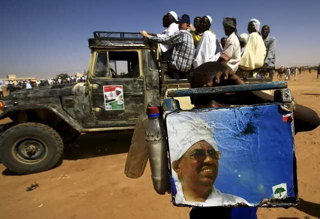 A shoe cleaner holds a picture of National Congress Party's (NCP) presidential candidate, Sudan's President Omar Hassan al-Bashir during a campaign rally at Al Fashir in North Darfur, ahead of the 2015 elections, April 8, 2015. (Photo by Mohamed Nureldin Abdallah/Reuters)