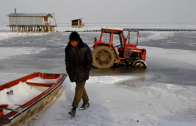 A fisherman walks next to the boat stuck in the frozen Dojran lake, Macedonia January 11, 2017. (Photo by Ognen Teofilovski/Reuters)