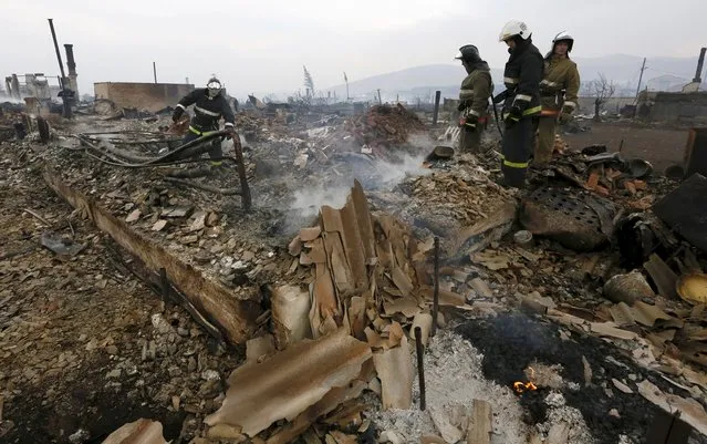 Firefighters search for the body of an elderly woman, who presumably was killed by the fire, amidst the debris of her house in the settlement of Shyra, damaged by recent wildfires, in Khakassia region, April 13, 2015. (Photo by Ilya Naymushin/Reuters)