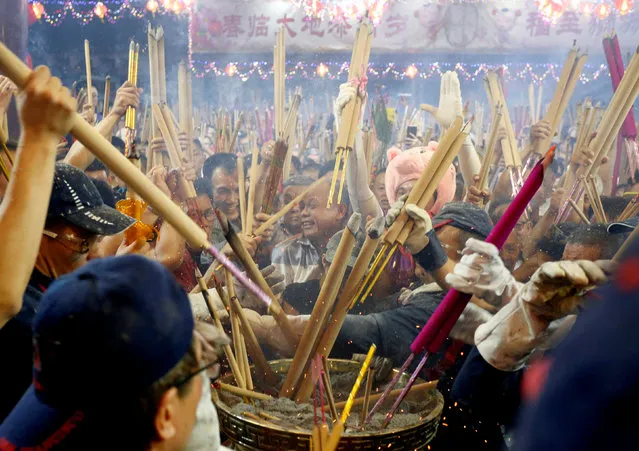 People rush to plant the first joss stick of the Lunar New Year of the Pig at the stroke of midnight at the Kwan Im Thong Hood Cho temple in Singapore, February 4, 2019. (Photo by Feline Lim/Reuters)