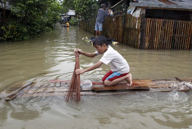 A boy uses a broom to paddle a makeshift raft along a flooded road in Butuan city in southern Philippine island of Mindanao January 17, 2014. The death toll from the floods and landslides in Mindanao caused by a lingering low-pressure area climbed to 34 on Friday, while more than 300,000 people are displaced due to flooding and landslides, the National Disaster Risk Reduction and Management Council reported. (Photo by Erik De Castro/Reuters)