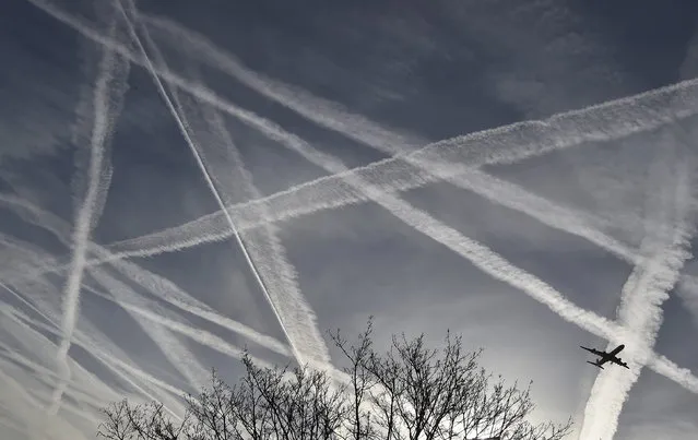 A passenger plane flies through aircraft contrails in the skies near Heathrow Airport in west London, April 12, 2015. (Photo by Toby Melville/Reuters)