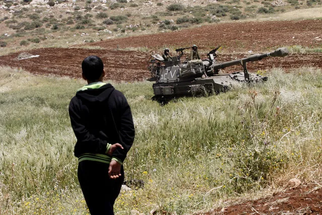 A Palestinian farmer watches Israeli troops during a military exercise in the West Bank village of Khirbet al-Tawil, near Nablus, 03 May 2015. Crops are threatened as the Israeli Army conducts wide-scale drills in the region, according to media reports. (Photo by Alaa Badarneh/EPA)