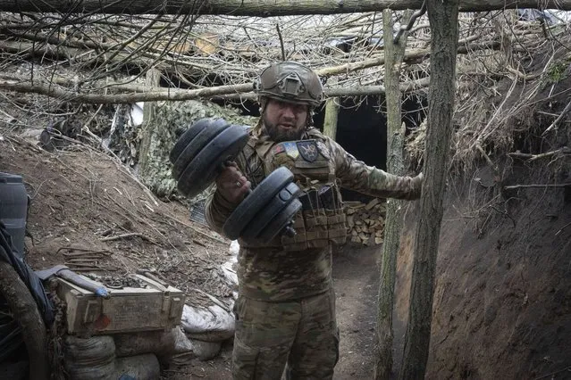 A Ukrainian serviceman of the 28th Separate Mechanised Brigade shows his dumbbells in a trench at the front line, near Bakhmut, Donetsk region, Ukraine, Sunday, March 3, 2024. (Photo by Efrem Lukatsky/AP Photo)