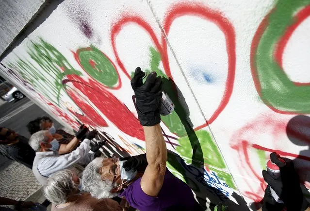 A woman sprays her design on a wall during a graffiti class offered by the LATA 65 organization in Lisbon, Portugal May 14, 2015. (Photo by Rafael Marchante/Reuters)