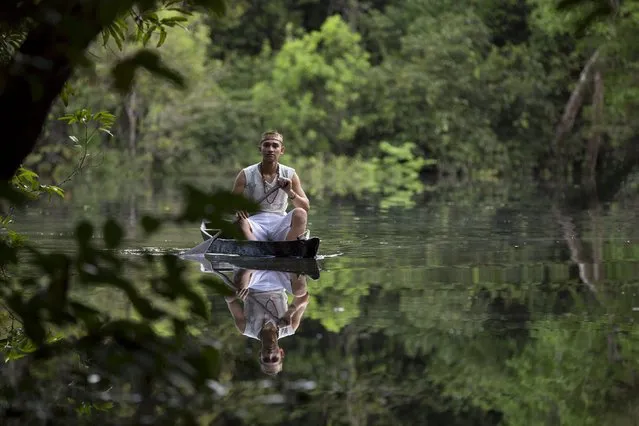 Kambeba Indian, Dream Braga (R), 18, rows his canoe near the village Tres Unidos, Amazon state May 9, 2015. (Photo by Bruno Kelly/Reuters)