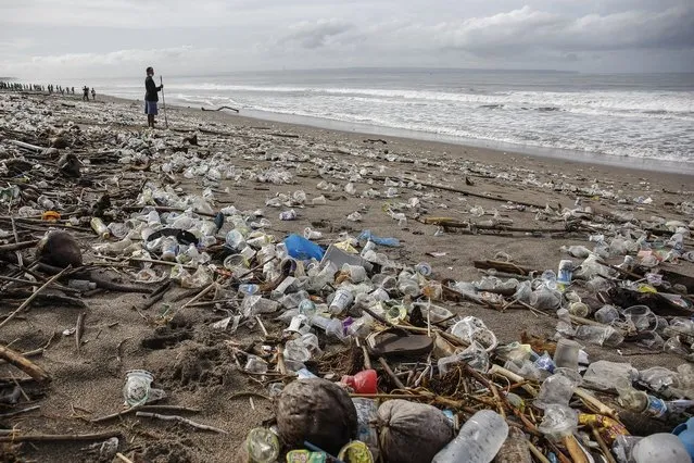 A man stands among plastic trashes that washed ashore in Berawa Beach, Bali, Indonesia on December 12, 2021. Tons of marine pollutions washed ashore along the coastline during monsoon season making Bali's popular beach covered with plastic rubbish, woods and other discarded materials. (Photo by Johannes P. Christo/Anadolu Agency via Getty Images)