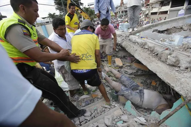 Volunteers rescue a body from a destroyed house after a massive in earthquake in Pedernales, Ecuador, Sunday, April 17, 2016. (Photo by Dolores Ochoa/AP Photo)