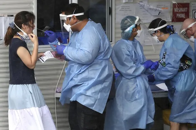 Health workers attend at a COVID-19 testing site in Brisbane, Australia Friday, January 7, 2022. Australia’s most populous state reinstated some restrictions and suspended elective surgeries on Friday as COVID-19 cases surged to another new record. (Photo by Jono Searle/AAP Image via AP Photo)