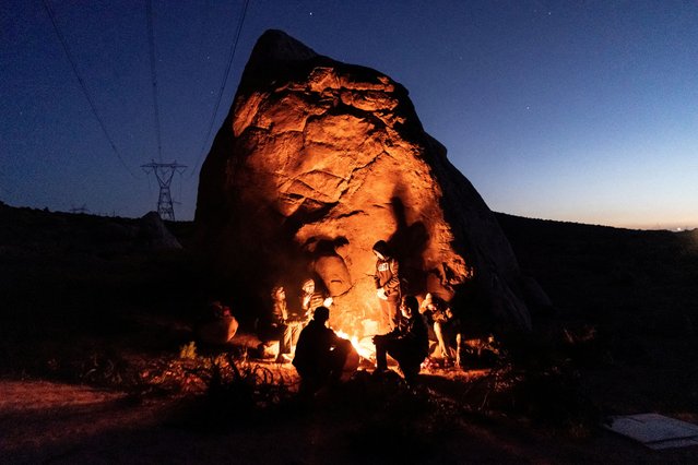 Asylum-seeking migrants from India and Colombia sit around fire to keep warm while waiting to be picked up by the U.S. Border Patrol after crossing the border from Mexico into the U.S. in Jacumba Hot Springs, California, U.S. April 27, 2024. (Photo by Go Nakamura/Reuters)