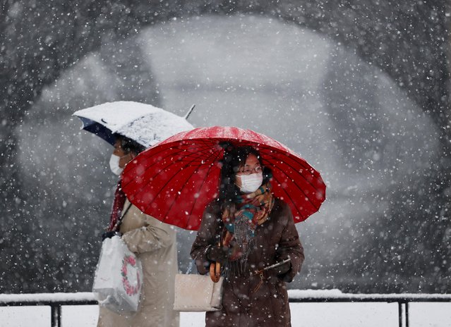 People wearing protective face masks visit the snow-covered Imperial Palace, amid the coronavirus disease (COVID-19) pandemic, in Tokyo, Japan on January 6, 2022. (Photo by Issei Kato/Reuters)