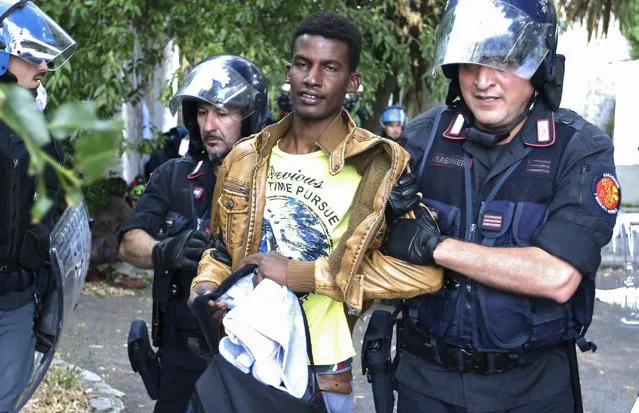 A migrant is evacuated by Italian policemen at the Franco-Italian border near Menton, southeastern France, Tuesday, June 16, 2015. Some 150 migrants, principally from Eritrea and Sudan, have been trying since last Friday to cross the border from Italy but have been blocked by French and Italian police. (AP Photo/Lionel Cironneau)