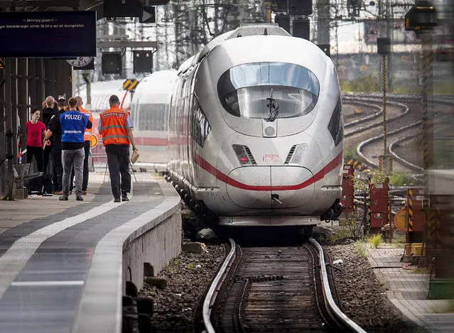 A police officer walks next to an ICE highspeed train at the main station in Frankfurt, Germany, Monday, July 29, 2019. An 8-year-old boy was run over by a train and killed at Frankfurt's main station on Monday after a man pushed him and his mother onto the tracks. The mother was able to escape but the boy was hit and run over by the train and suffered fatal injuries. (Photo by Michael Probst/AP Photo)