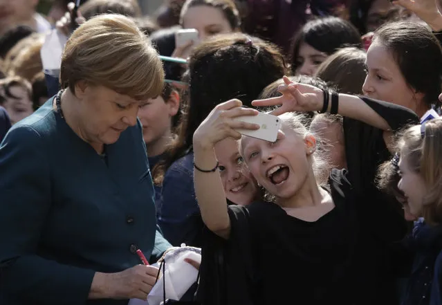 A girl grimaces for a selfie as German Chancellor Angela Merkel, left, arrives for a European project day at the Lycee Francais school in Berlin, Germany, Tuesday, May 3, 2016. (Photo by Markus Schreiber/AP Photo)
