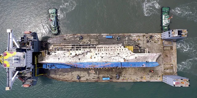 The sunken ferry Sewol is seen on a semi-submersible transport vessel in waters off Mokpo, South Korea. Friday, March 31, 2017. The corroding 6,800-ton ferry raised from the bottom of the sea last week arrived at a South Korean port Friday, where it will be searched for the remains of nine missing passengers from a 2014 sinking. (Photo by Kim Do-hun/Yonhap via AP Photo)