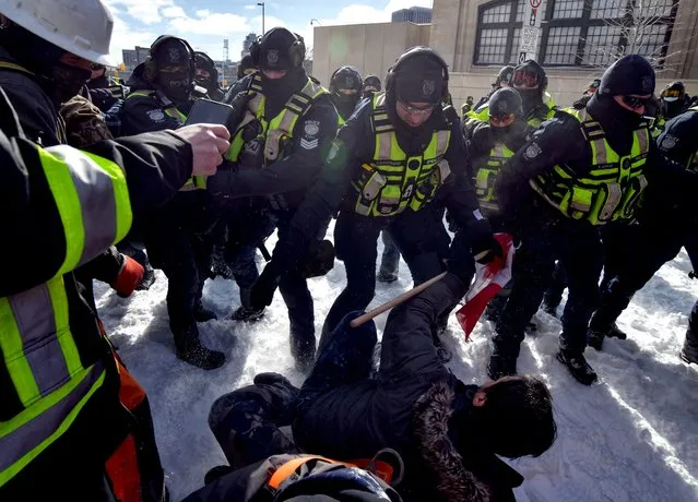 Police clash with demonstrators against Covid-19 mandates in Ottawa on February 18, 2022. Canadian police on Thursday began a massive operation to clear the trucker-led protests against Covid health rules clogging the capital for three weeks, with several arrests made. (Photo by Ed Jones/AFP Photo)