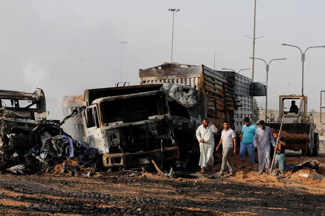 Iraqi men inspect the site of a suicide truck bomb at a checkpoint in the south of the Iraqi capital Baghdad, Iraq March 30, 2017. (Photo by Ahmed Saad/Reuters)