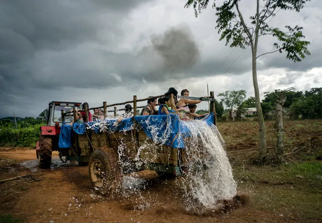 In this August 24, 2019 photo, a tractor pulls a trailer that was converted into a swimming pool as it drives along the roads of El Infernal neighborhood in San Andres in the province of Pinar del Río, Cuba. The idea for the mobile tractor-pool was hatched by local parents, to make their kids happy and fight the harsh Caribbean heat. (Photo by Ramon Espinosa/AP Photo)