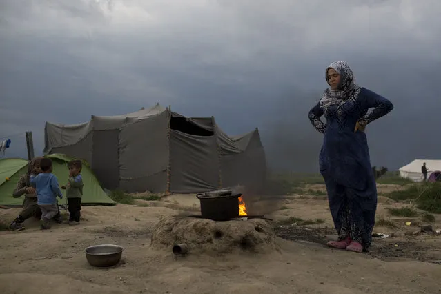 A Syrian woman cooks at the northern Greek border point of Idomeni, Greece, on Tuesday May 10, 2016. About 54,000 refugees and migrants are currently stranded in Greece as 10,000 are camped in Idomeni, after the European Union and Turkey reached a deal designed to stem the flow of refugees into Europe's prosperous heartland. (Photo by Petros Giannakouris/AP Photo)