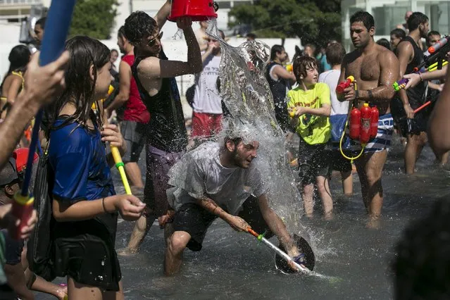 A participant pours water on another during a water fight in Tel Aviv, July 10, 2015. (Photo by Baz Ratner/Reuters)