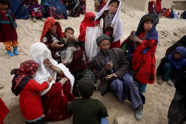 In this Sunday, May 4, 2014 photo, Survivors wait to receive donations near the site of Friday's landslide that buried Abi-Barik village in Badakhshan province, northeastern Afghanistan. Stranded and with no homes, many of the families have struggled to get aid. Some have gone to nearby villages to stay with relatives or friends. (Photo by Massoud Hossaini/AP Photo)