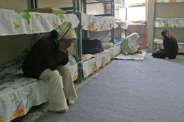 Iranian women try to hide their faces inside a prison cell in the women's section of the Evin prison in north Tehran on Tuesday, 13 June 2006. Most of the convicts are jailed for drugs use. (Photo by Abedin Taherkenareh/EPA)