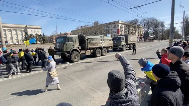A demonstrator gestures as others, displaying Ukrainian flags, chant “go home” and walk towards Russian military vehicles at a pro-Ukraine rally amid Russia's invasion, in Kherson, Ukraine March 20, 2022 in this still image from video. (Photo by Reuters/Stringer)