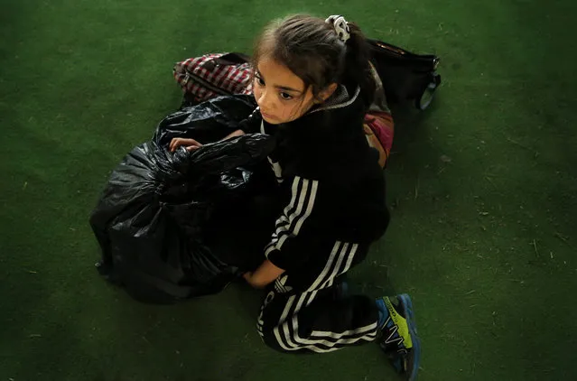 A Syrian girl who is newly displaced by the Turkish military operation in northeastern Syria, sits next to her belongings upon her arrival at the Bardarash camp, north of Mosul, Iraq, Wednesday, October 16, 2019. The camp used to host Iraqis displaced from Mosul during the fight against the Islamic State group and was closed two years ago. The U.N. says more around 160,000 Syrians have been displaced since the Turkish operation started last week, most of them internally in Syria. (Photo by Hussein Malla/AP Photo)