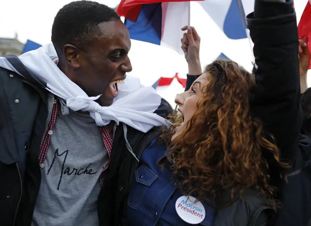 Supporters of French independent centrist presidential candidate, Emmanuel Macron react outside the Louvre museum in Paris, France, Sunday, May 7, 2017. Polling agencies have projected that centrist Emmanuel Macron will be France's next president, putting a 39-year-old political novice at the helm of one of the world's biggest economies and slowing a global populist wave. The agencies projected that Macron defeated far-right leader Marine Le Pen 65 percent to 35 percent on Sunday. (Photo by Laurent Cipriani/AP Photo)