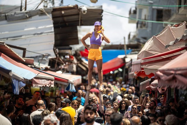 Acrobats perform at the Carmel market, amid the ongoing conflict between Israel and the Palestinian Islamist group Hamas, in Tel Aviv, Israel on May 24, 2024. (Photo by Marko Djurica/Reuters)