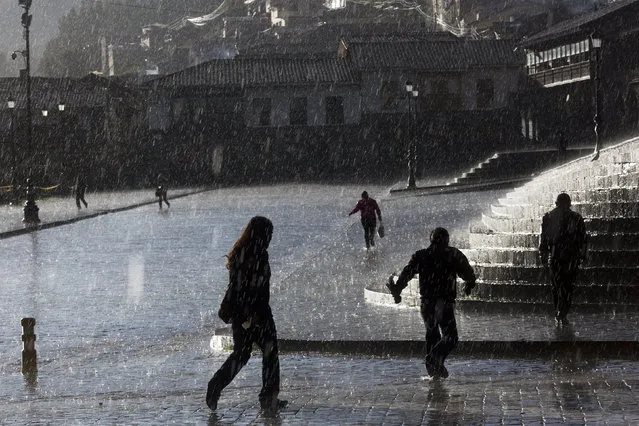 People walk under a heavy rain downtown in Cusco, Peru, Wednesday, May 25,  2016. Cusco was the historic capital of the Inca Empire from the 13th into the 16th century until the Spanish conquest. (Photo by Rodrigo Abd/AP Photo)