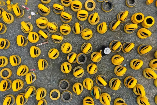 This aerial photo taken on April 17, 2022 shows a staff member painting upcycled tyres to be used in a go-karting track at a park in Ningbo in China's eastern Zhejiang province. (Photo by AFP Photo/China Stringer Network)