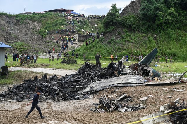 People stand at the site after a Saurya Airlines' plane crashed during takeoff at Tribhuvan International Airport in Kathmandu on July 24, 2024. A passenger plane carrying 19 people crashed during takeoff in Kathmandu on July 24 with the pilot surviving but “many” others aboard dead, police in the Nepali capital told AFP. (Photo by Prakash Mathema/AFP Photo)